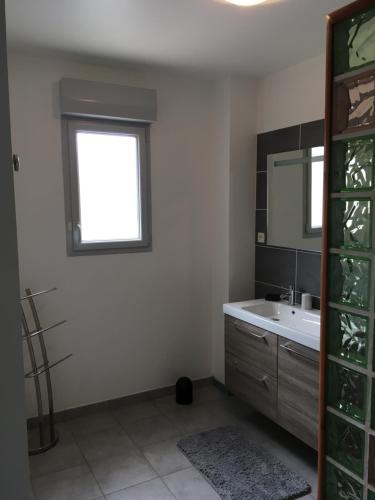 baño con lavabo, ventana y espejo en lemarinel, en Barneville-Carteret