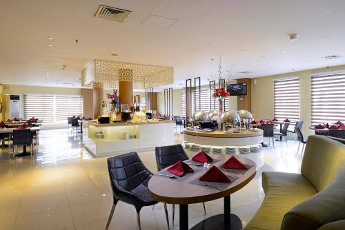 a lobby with tables and chairs and a restaurant at CROWN PRINCE Hotel Surabaya Managed by Midtown Indonesia in Surabaya