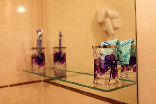 una estantería de cristal en un baño con flores. en Totem Hotel, en Shymkent