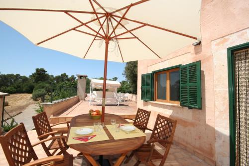 a wooden table and chairs with an umbrella on a patio at Finca Agroturismo Sa Cova den Borino in Campos