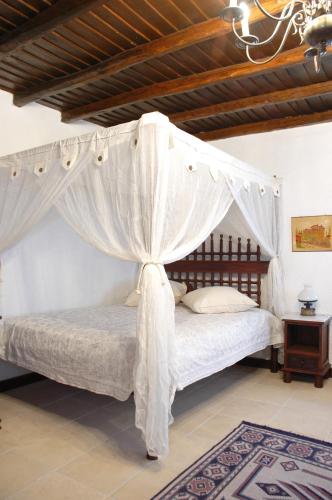 a bedroom with a canopy bed with white curtains at Katsaneiko Mansion in Afitos
