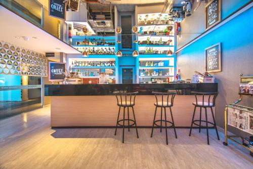a bar in a restaurant with three bar stools at CROWN PRINCE Hotel Surabaya Managed by Midtown Indonesia in Surabaya