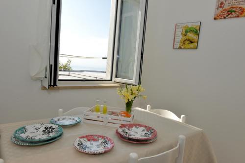 a dining room table with four plates and a window at Sweet Home Positano in Positano