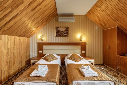 two beds in a room with wooden walls at Status Hotel in Lviv