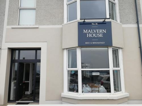 a store with a sign on the front of a building at Malvern House in Portrush