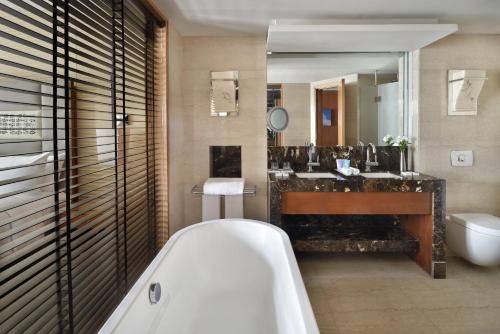 a bathroom with a tub and a sink and a mirror at Sankara Nairobi, Autograph Collection in Nairobi