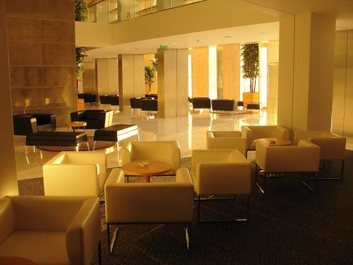 a lobby with white chairs and a table and chairs at VIP Executive Azores Hotel in Ponta Delgada