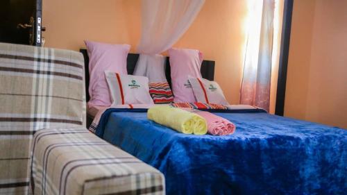 łóżko z poduszkami na górze obok kanapy w obiekcie Mangalita Lodges Entebbe w mieście Entebbe