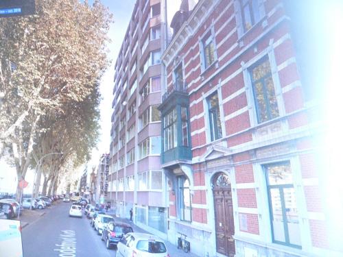 a red brick building on a city street with parked cars at Liège centre 13 Quai Godefroid Kurth POUR 2 PERS à 25 min gare Guillemins in Liège