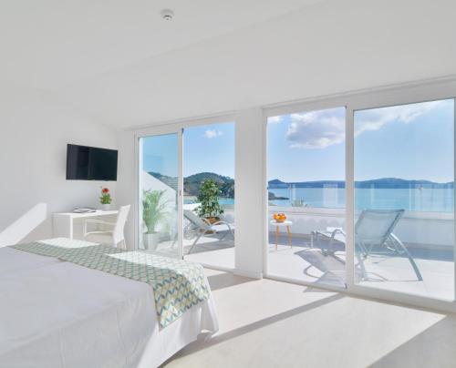 a white bedroom with a view of the ocean at Paguera Treff Boutique Hotel in Paguera