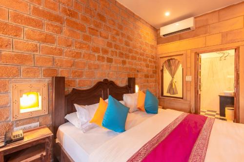 a bedroom with a brick wall and a bed with colorful pillows at Boutique Helsinki in Jaisalmer