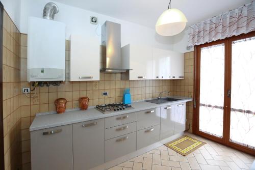 een keuken met witte kasten, een wastafel en een raam bij Appartamento Martina C. in Marghera