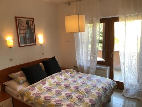 a bedroom with a bed with a colorful comforter and a window at Apartments Lukas in Medulin