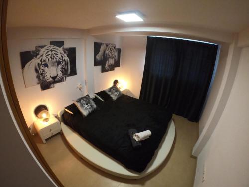 sypialnia z dużym czarnym łóżkiem z plakatami na ścianie w obiekcie Apartamento a primera linea de mar en platja d’aro w mieście Platja  d'Aro