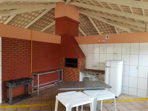 a kitchen with white tables and a brick wall at Apartamento Caldas in Caldas Novas