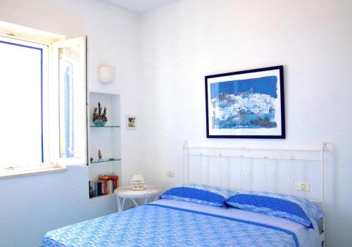 ein Schlafzimmer mit einem Bett und einem Bild an der Wand in der Unterkunft Casa Acquamarina in Villanova di Ostuni