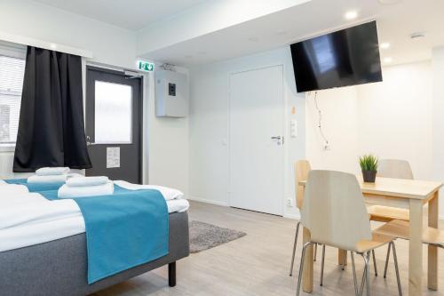 Cette chambre comprend deux lits, une table et une télévision. dans l'établissement Oma Hotelli, à Ylöjärvi