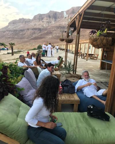 a group of people sitting on benches in the desert at Ein Gedi Camp Lodge in Ein Gedi