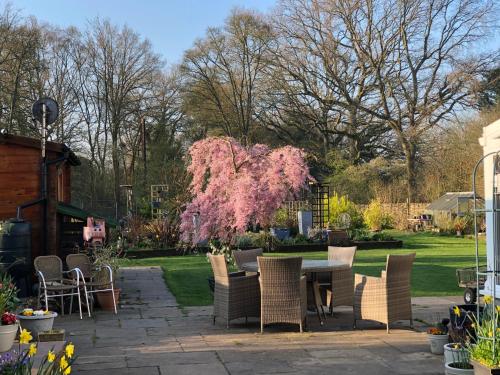 a patio with a table and chairs and a pink tree at West View Lodge in Basingstoke