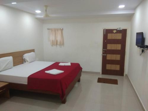 a bedroom with a bed with a red blanket at Raya's Inn in Kumbakonam