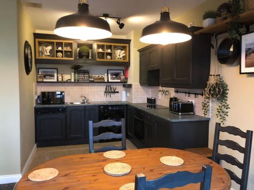 une cuisine avec une table en bois et des placards noirs dans l'établissement Sandy Cove Bundoran Sea Views Free Wifi Netflix Luxurious Apartment, à Bundoran