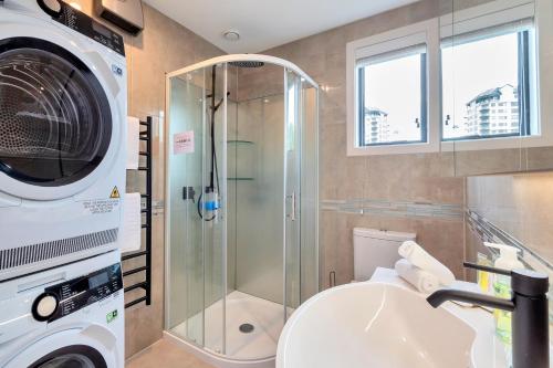 a bathroom with a shower and a washing machine at Greenwich Townhouse with Parking and Air-Con in Auckland