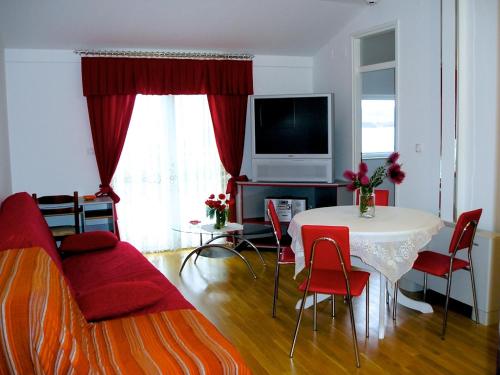 a living room with a table and red chairs at Vila Smirna in Sveti Filip i Jakov