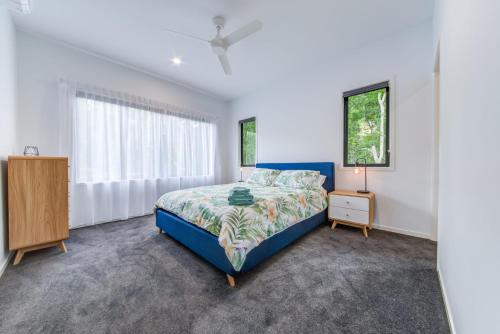 a bedroom with a blue bed and a window at Hillside Haven - Airlie Beach in Airlie Beach