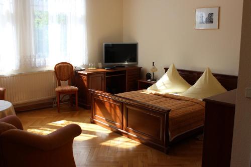 a bedroom with a bed and a desk with a television at Villa Jagdhaus in Wernigerode