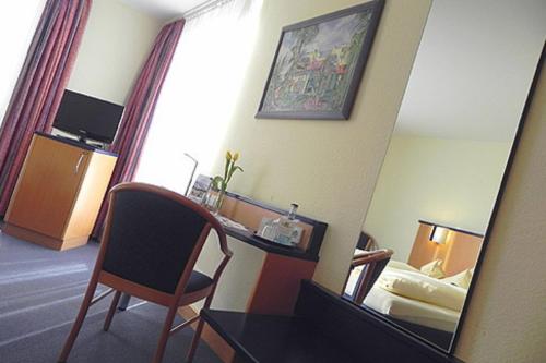 Habitación de hotel con escritorio y espejo en Hotel Alber, en Leinfelden-Echterdingen