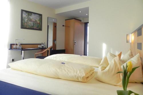 1 Schlafzimmer mit 2 Betten und weißen Kissen in der Unterkunft Hotel Alber in Leinfelden-Echterdingen