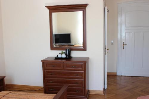 a room with a dresser with a mirror and a television at Villa Jagdhaus in Wernigerode