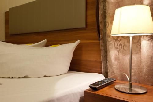 a bed with a lamp and a remote control on a table at Arena am Zoo in Frankfurt