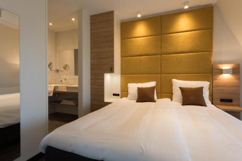 a bedroom with a large white bed and a bathroom at Hotel Kaap West I Kloeg Collection in Westkapelle