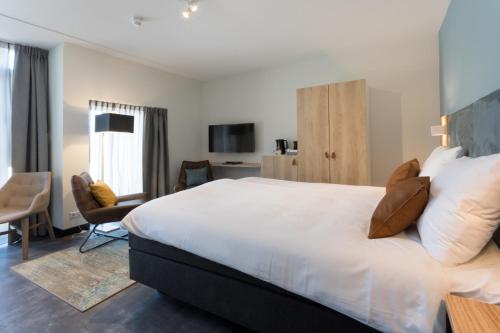 a bedroom with a large white bed and a desk at Hotel Kaap West I Kloeg Collection in Westkapelle