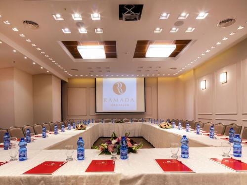 a conference room with tables and chairs and a screen at Ramada Jerusalem Hotel in Jerusalem
