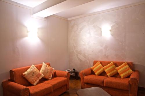 two orange chairs in a living room with lights on the wall at Hotel La Luna in Lucca