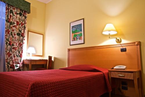 a hotel room with a red bed and a telephone at Hotel La Luna in Lucca