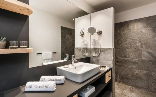 a bathroom with a sink, mirror, and bathtub at Hotel Gasserhof in Bressanone