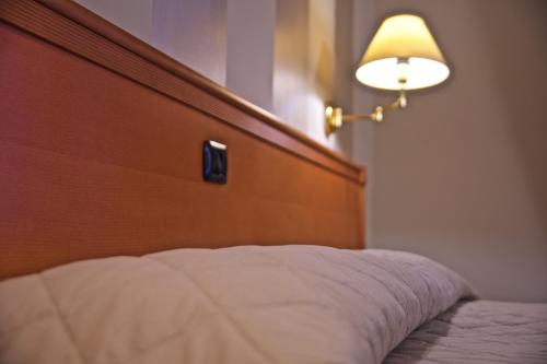 a bed with a wooden head board and a lamp at Hotel La Luna in Lucca