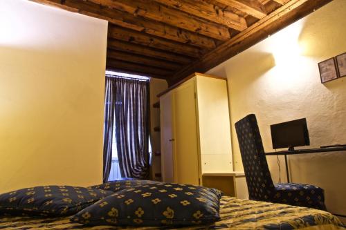 a bedroom with a bed and a chair and a window at Hotel La Luna in Lucca