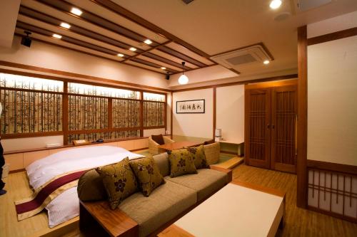 a bedroom with a couch and a bed and windows at Hotel Bintang Pari Resort (Adult Only) in Kobe