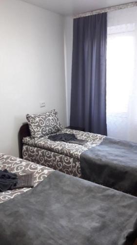 a room with two beds and a window with blue curtains at КП ДР Готель in Drogobych
