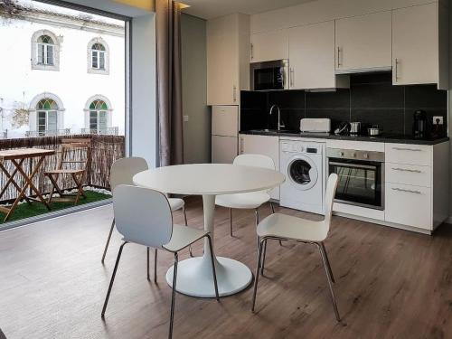 a kitchen with a white table and chairs and a table and a kitchen with at Julio Apartment in Faro - Down Town Center in Faro