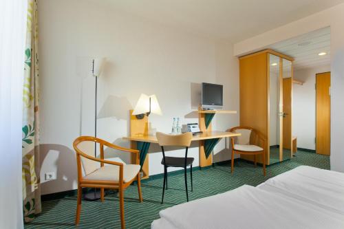 une chambre d'hôtel avec un bureau et deux chaises dans l'établissement HKK Hotel Wernigerode, à Wernigerode