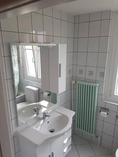 a white bathroom with a sink and a mirror at Chambres meublées Prilly - Lausanne in Prilly