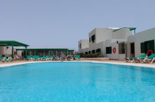 una piscina con sedie, tavoli e edifici di Relax Tiñosa Apartment a Puerto del Carmen