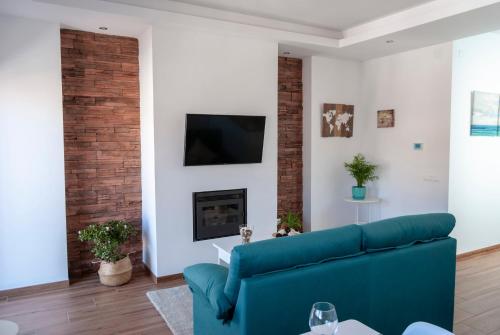 a living room with a blue couch and a fireplace at Apartamentos Cantarería, Jazmín. in Setenil