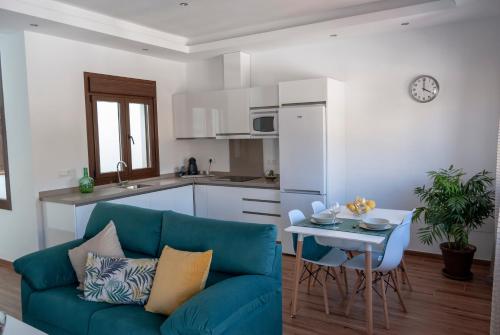 ein Wohnzimmer mit einem blauen Sofa und einem Tisch in der Unterkunft Apartamentos Cantarería, Jazmín. in Setenil de las Bodegas