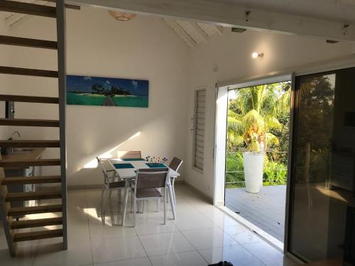 a dining room with a table and a glass door at Bungalow Bambou in Petit-Bourg